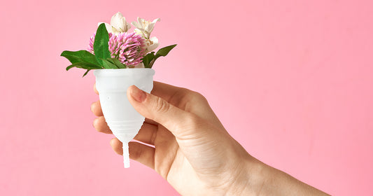 woman holding period cup with flowers