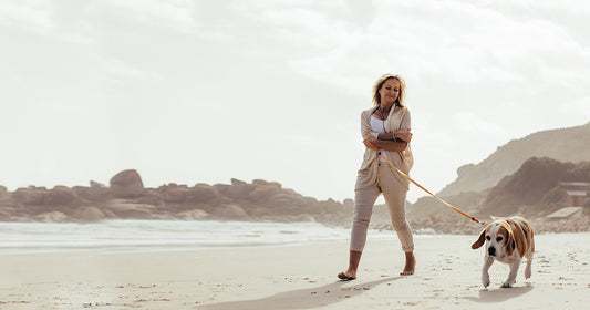 happy woman walking dog on beach