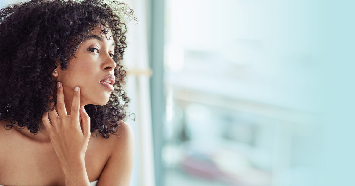 woman looking at skin in mirror