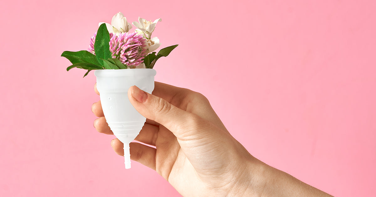 woman holding period cup with flowers